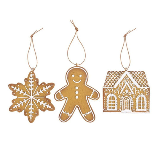 Three brown gingerbread biscuit decorations hang from strings: a snowflake with white icing details, a smiling gingerbread person, and a decorated house—perfect as charming Christmas tree ornaments.
