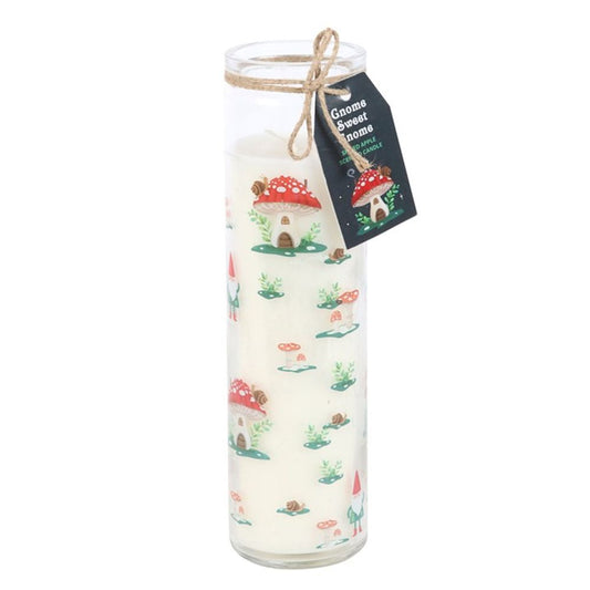 Tall glass candle with a whimsical design featuring red-capped mushroom houses, snails, and small gnomes amidst green foliage. A twine-tied tag reads Gnome Sweet Gnome with a mushroom illustration. Enjoy hints of spiced apple as it burns.