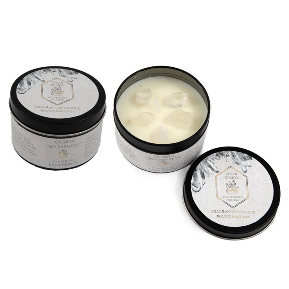 Three scented candles in round metal tins with black lids make a thoughtful gift. Two, closed, display elegant labels featuring text and a quartz graphic. The open candle reveals white wax adorned with clear quartz crystals. These sophisticated designs include the fresh linen scented candle among them.