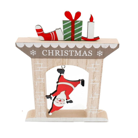 A festive fireplace Christmas decoration with CHRISTMAS on the mantelpiece, topped with a stocking, present, and candle. A cut-out shows Father Christmas hanging upside down inside the fireplace, smiling.