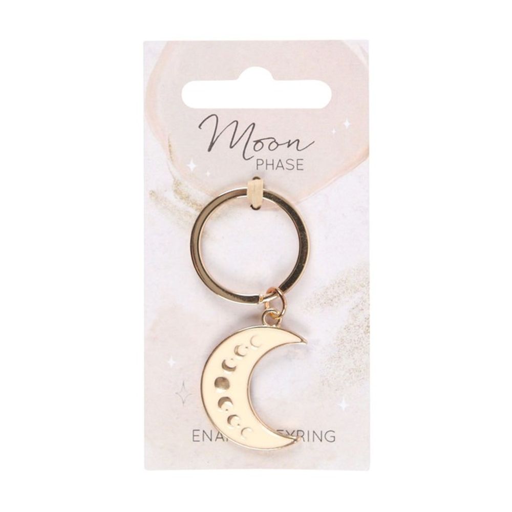 Gold crescent moon keyring with an enamelled crescent charm and moon phase cut-outs on a white backing card. The card features Moon Phase in cursive and faint celestial illustrations. A round loop secures the charming keyring to the card.