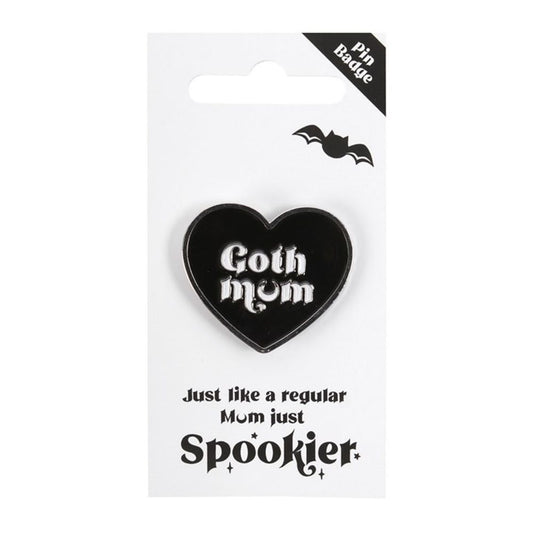 A black heart pin badge featuring white text reading Goth Mum in Gothic font. Its mounted on a white card adorned with a small black bat illustration. Below, the whimsical text declares, Just like a regular Mum, just Spookier. Perfect for the alternative mum in your life.