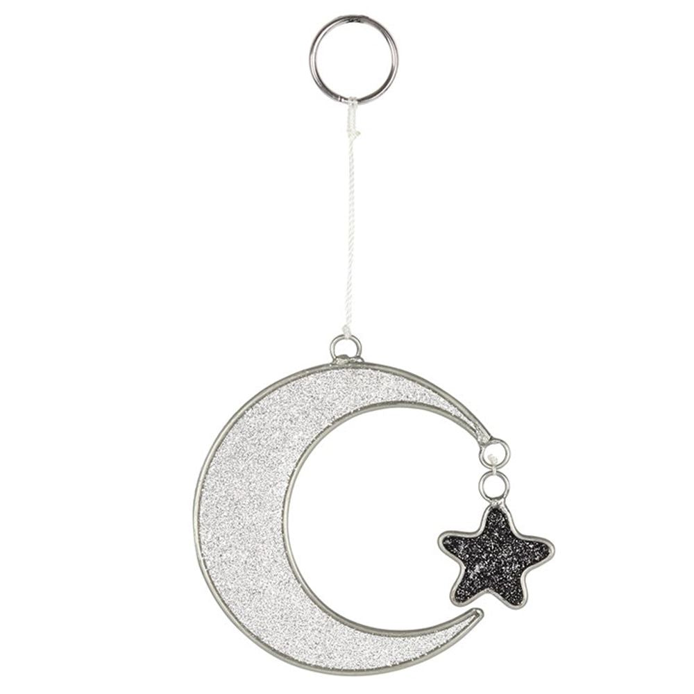 A dazzling keyring with a moon and star design, this piece sparkles and glimmers as it catches the light. The crescent moon shimmers with silver glitter, while the star shines in black. Connected by a metal frame, they dangle from a white cord linked to a silver ring. Perfect for adding a magical touch to your keys!.