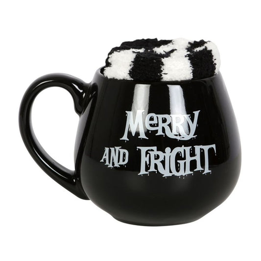 A black mug featuring the phrase “Merry and Fright” in a festive, spooky font sits against a white background; this mug and sock gift set is perfect for cosy winter nights.