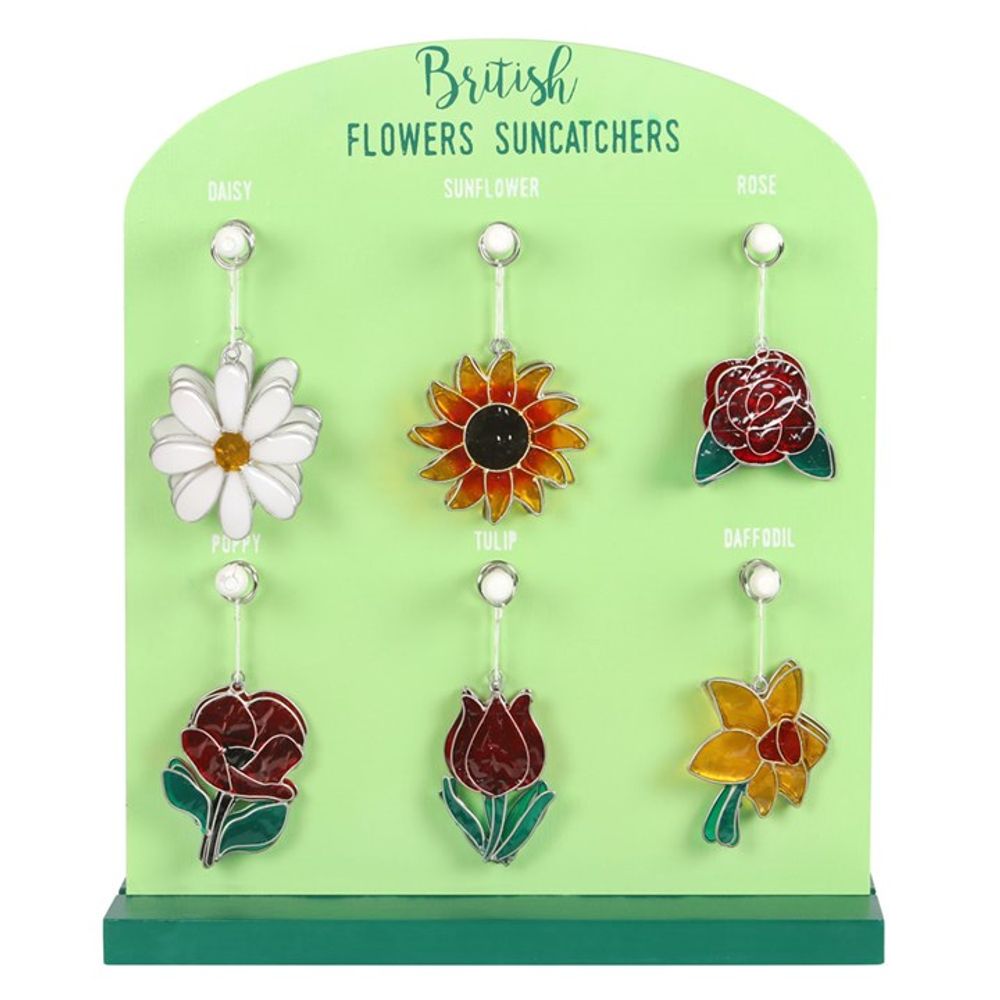 A green display board labelled ‘British Flowers Suncatchers’ holds six colourful stained-glass suncatchers featuring British flower designs—daisy, sunflower, rose, peony, tulip and daffodil—perfect as garden decorations.