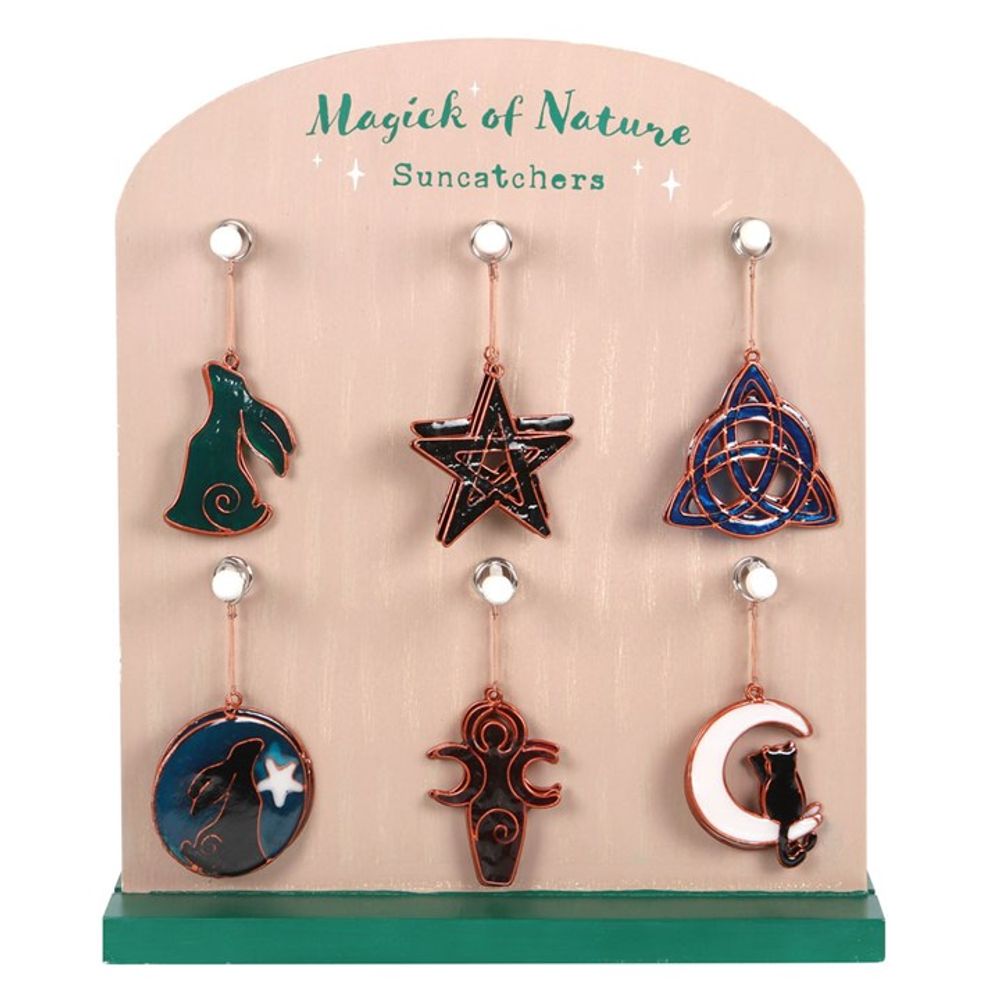 A display board labelled Magick of Nature Suncatchers holds six hanging suncatchers, each featuring Pagan symbolism: a green rabbit, pentagram, triquetra, wolf with star, triple moon goddess, and black cat on a crescent moon.