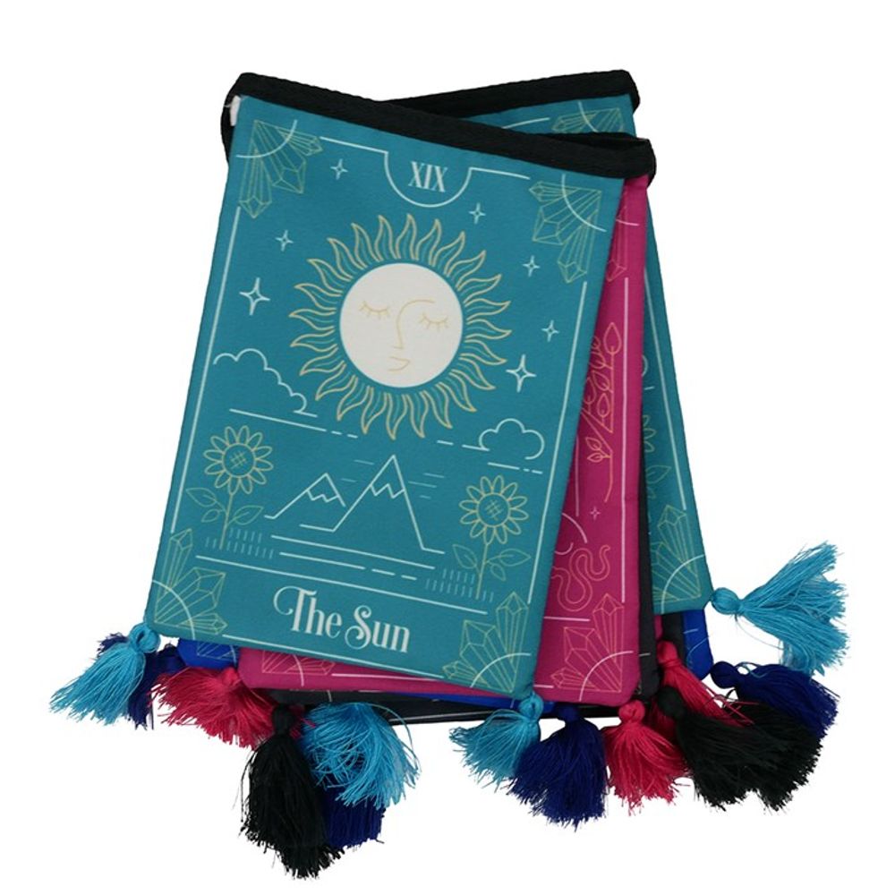 Tarot-themed pouches with tassels embody a mystical ambience, showcasing The Sun card design. Featuring sun, mountains, and flowers in teal, pink, and black hues, the modern tarot card designs are complemented by contrasting blue, pink and black tassels.