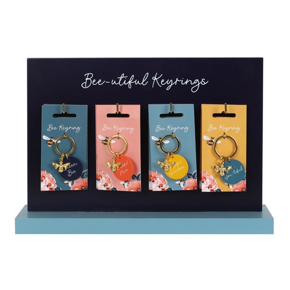 A retail display labelled Bee-utiful Keyrings holds four floral-themed keyrings—each featuring a bee charm and a round, colourful tag—perfect as a cheerful Mother’s Day gift.