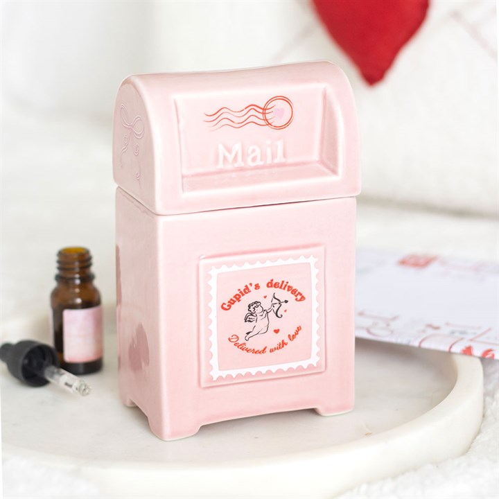 A pink, postbox-shaped ceramic box with Mail embossed on the lid and Cupids delivery, Delivered with love on the front—ideal as a Valentine’s Day home décor item. Dropper bottle and letter are included.
