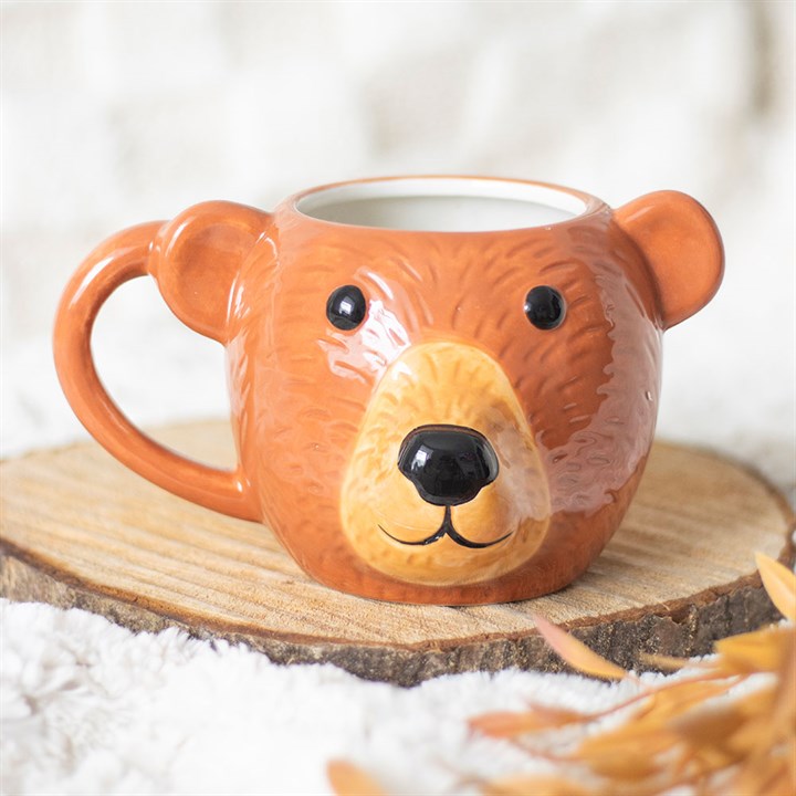 A bear-shaped ceramic mug with textured brown fur, round black eyes, a raised nose, and a friendly smile sits on a wooden slice—a charming addition to your unique mug collection. Hand wash only.