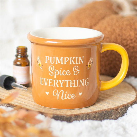 A brown mug with a yellow handle sits on a wooden coaster. Nearby, an autumn-themed wax melt adds to the cosy scene. The mug reads Pumpkin Spice & Everything Nice in white letters, with small decorative leaves.