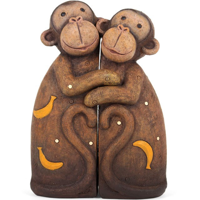 Two brown resin monkey family figurines with carved smiles sit hugging side by side, their bodies adorned with yellow banana shapes and swirls. Their tails curve together to form a heart-like shape—a charming decorative ornament.