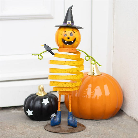 A whimsical pumpkin man with a spiral body, witchs hat, and blue boots stands smiling, holding a blackbird. Behind him are festive pumpkins—perfect as autumnal home décor or as a Halloween decoration for your doorstep.