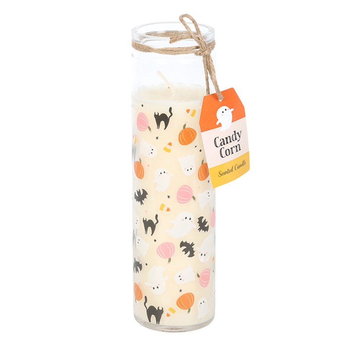 A tall tube candle decorated with Halloween-themed illustrations of ghosts, black cats, bats, candy corn, and pumpkins; a twine bow and a tag labelled Candy Corn Scented Candle are attached at the top.