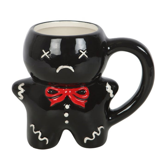 A black gingerdead man mug, shaped like a gingerbread figure with a downturned mouth and X eyes, adorned with a red bow tie and white icing details. Ideal as an unusual Christmas gift mug.