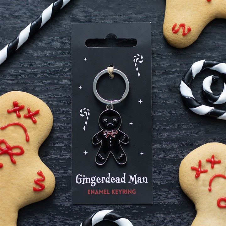 A black enamel gingerdead man keyring with skeleton details is displayed on a card, surrounded by festive accessories such as decorated biscuits and candy canes—perfect for fans of dark humour.