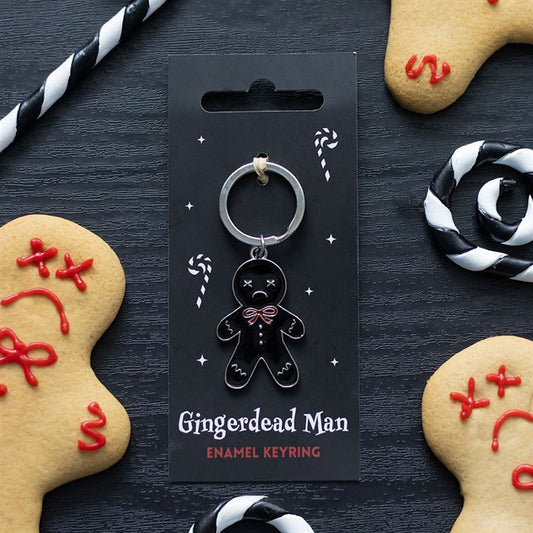 A black enamel gingerdead man keyring with skeleton details is displayed on a card, surrounded by festive accessories such as decorated biscuits and candy canes—perfect for fans of dark humour.