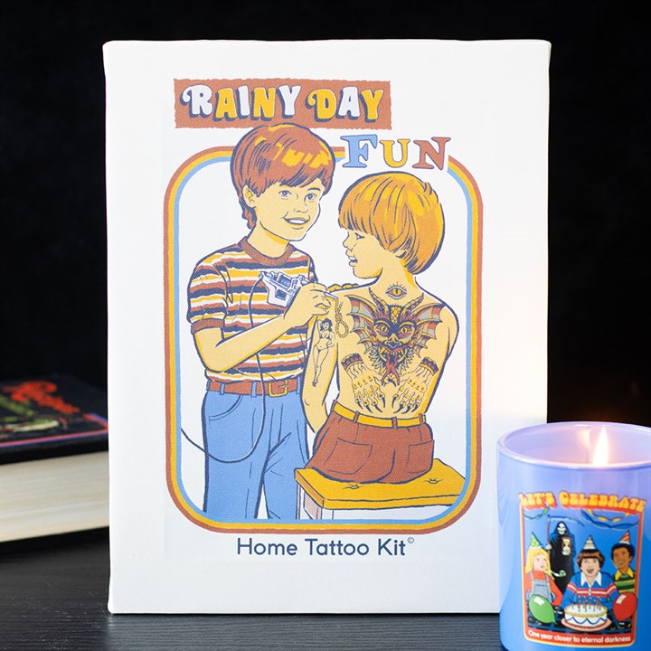 A book cover titled Rainy Day Fun Home Tattoo Kit features a Steven Rhodes retro-style illustration of two children; one is giving the other a tattoo with a pen, and the second childs arms and chest are covered in drawn-on tattoos.