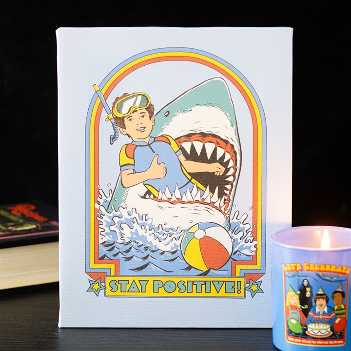 A retro-style illustration in the vein of a Steven Rhodes canvas depicts a smiling boy with snorkelling gear giving a thumbs-up while being attacked by a huge shark; perfect for fans of vintage gifts. “STAY POSITIVE!” is boldly written beneath.