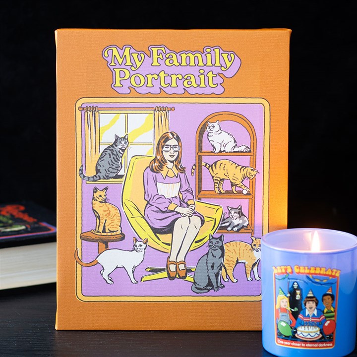 An illustrated canvas plaque titled “My Family Portrait” depicts a woman with glasses seated in a chair, surrounded by eight cats, with a lit decorative candle and a closed book in the retro, gift-inspired scene.