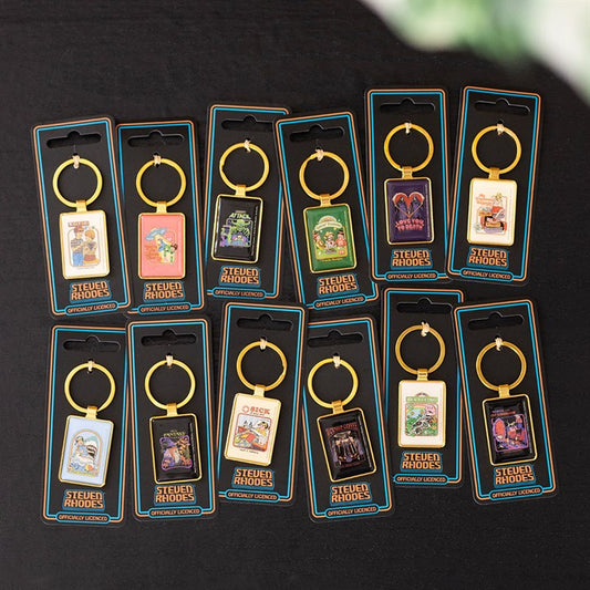 Twelve Steven Rhodes keyrings with retro-style illustrated designs are displayed on a black surface, each in its packaging with a gold ring and enamel keyring charm featuring quirky artwork and text—ideal retro gifts.