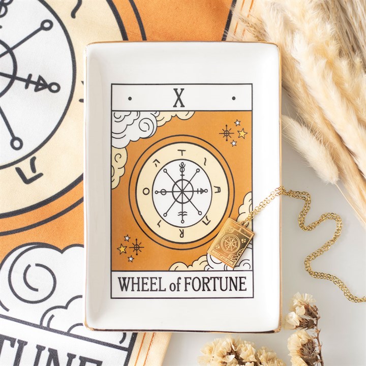 A rectangular tarot trinket dish features a gold and white Wheel of Fortune design, with a gold necklace placed on top. Nearby are dried flowers, pampas grass, and a matching patterned cloth from the Vintage Tarot collection.