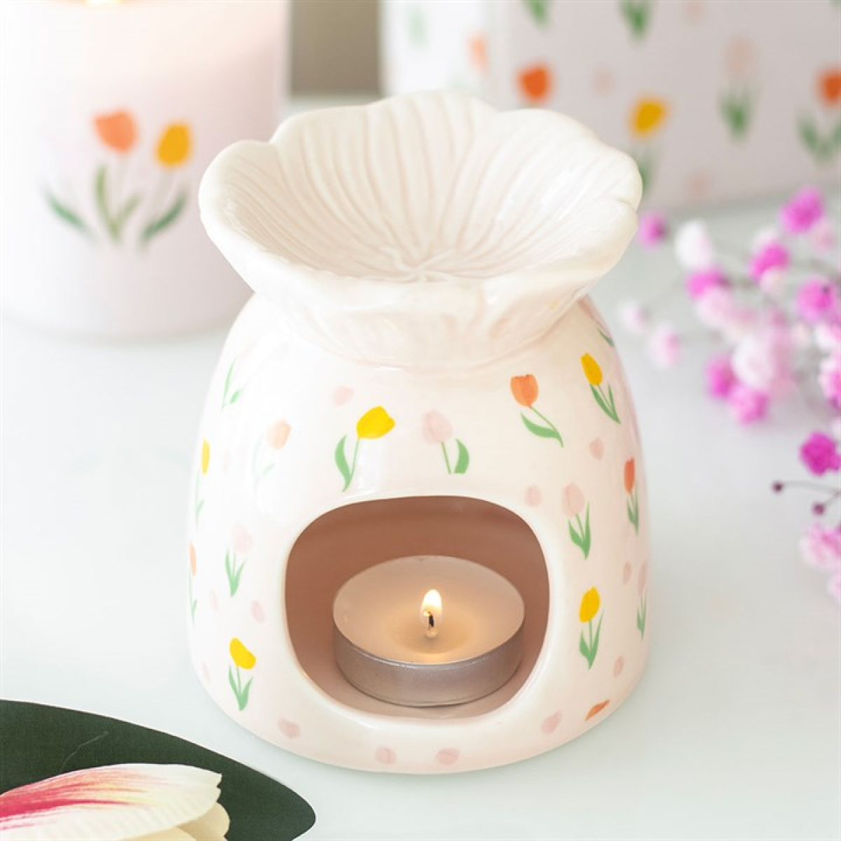 A candle in a tulip-patterned pot.