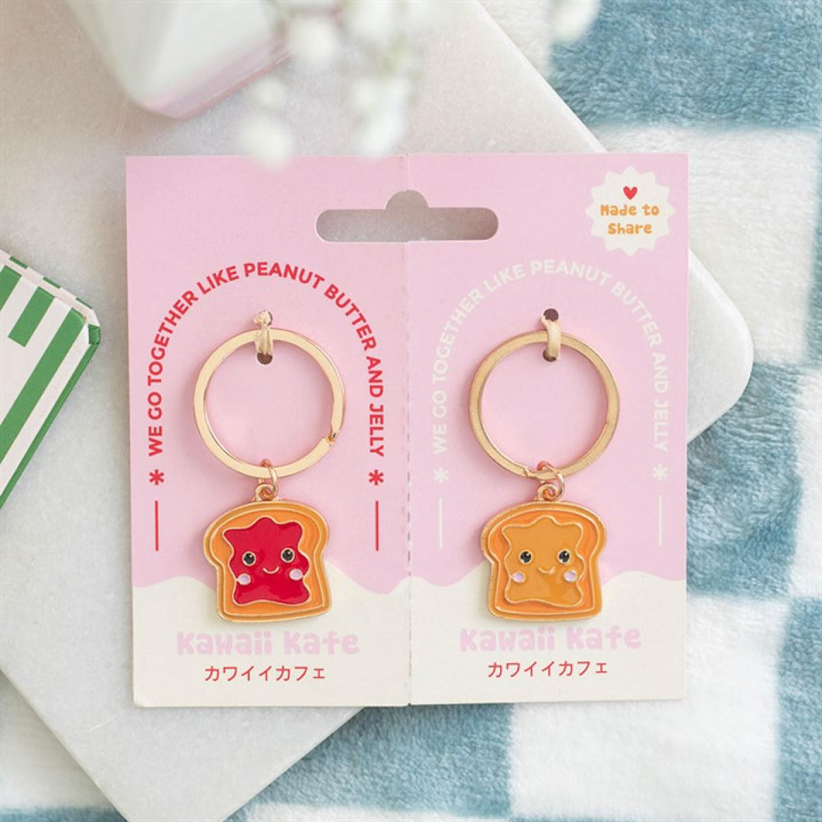 Two kawaii collectibles are shown on pink cards. Each Peanut Butter and Jelly keyring has an adorable toast charm—one with red jam, one with yellow peanut butter. The cards say “Kawaii Kafe” with Japanese text underneath.