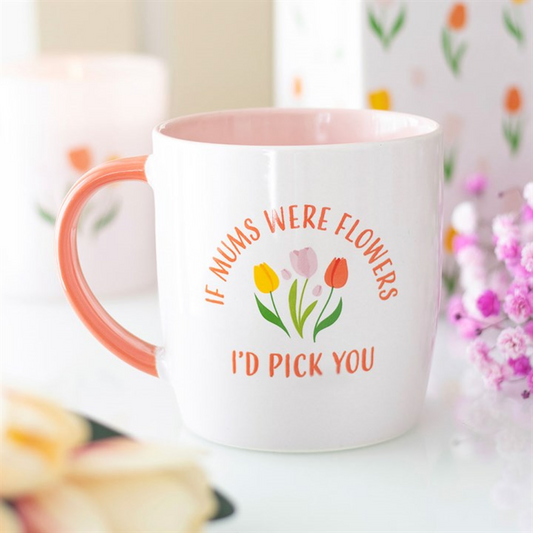 A ceramic Mother’s Day mug with a pink handle and interior displays three pastel tulips and the phrase “If mums were flowers I’d pick you.” An ideal gift for mum, with floral details and blurry shapes in the background.