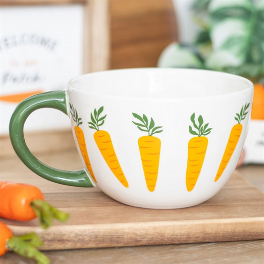 A delightful mug with a carrot motif and a green handle showcases a row of vivid carrots. Ideal as a gift for gardeners, this large teacup sits on wood among fresh carrots and softly blurred foliage.