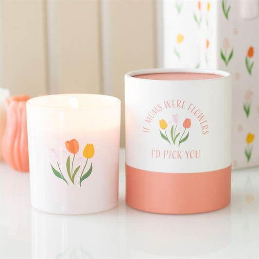 Two white French tulip-scented candles with pastel floral illustrations—one lit, one reading "IF MUMS WERE FLOWERS I’D PICK YOU"—make an ideal Mother’s Day gift in printed glass holders, with a floral box behind.